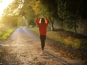 Cropped image focusing on a woman beginning a walking journey on a quiet nature road.