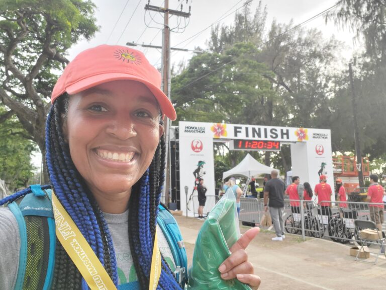 Kimberlee smiling at the finish line of the Honolulu Marathon after completing the event, demonstrating how small consistent walking habits can lead to extraordinary accomplishments over time.